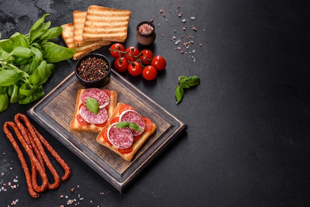 Spanish dried sausage salami on a dark concrete background. Preparation of delicious fresh sandwiches