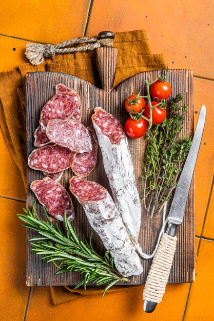 Spanish Fuet sausage slices on wooden cutting board Orange background Top view