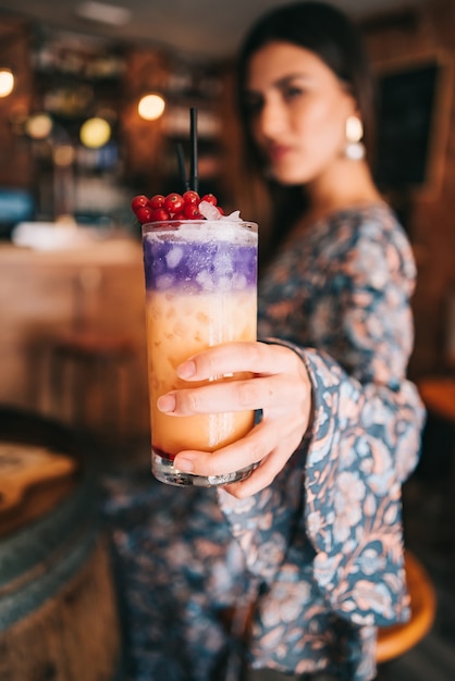 Spanish girl holding cocktail in hand shallow depth of field