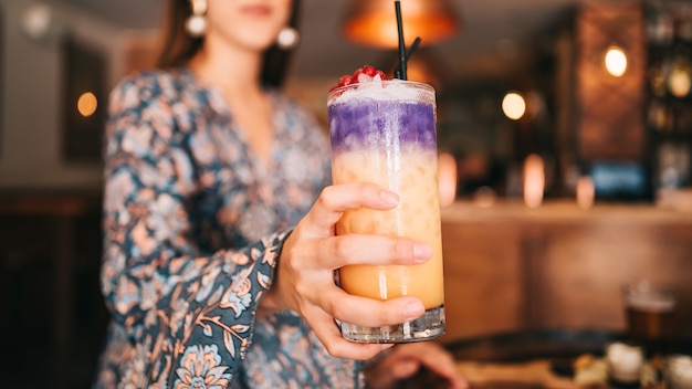 Spanish girl holding cocktail in hand shallow depth of field