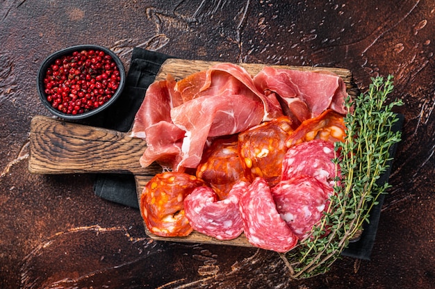 Spanish meat tapas - salami, jamon, choriso cured sausages. Dark background. Top view.