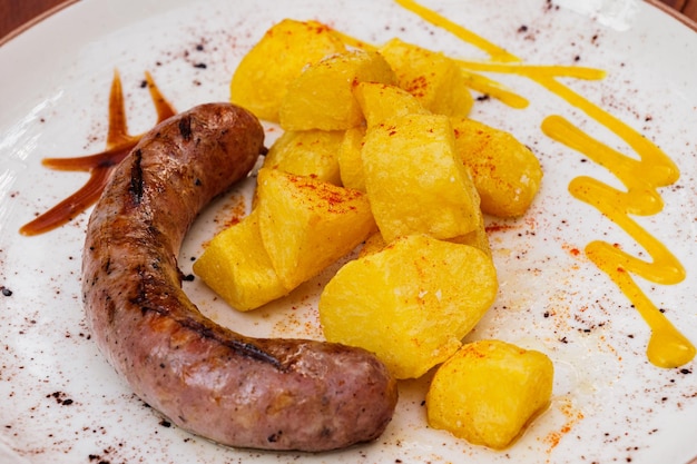 Spanish pork sausages butifarras with fried potatoes and sauces on white plate