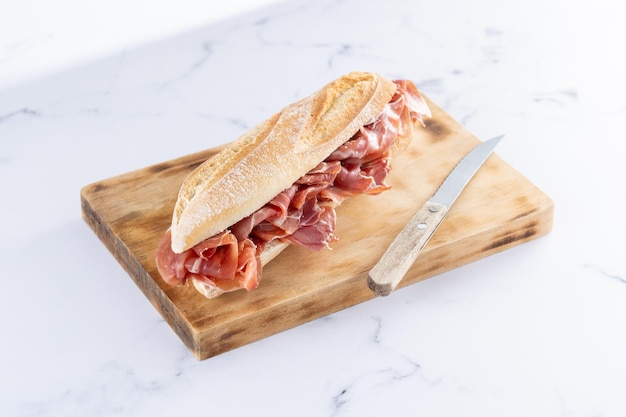 Spanish serrano ham sandwich on white marble background