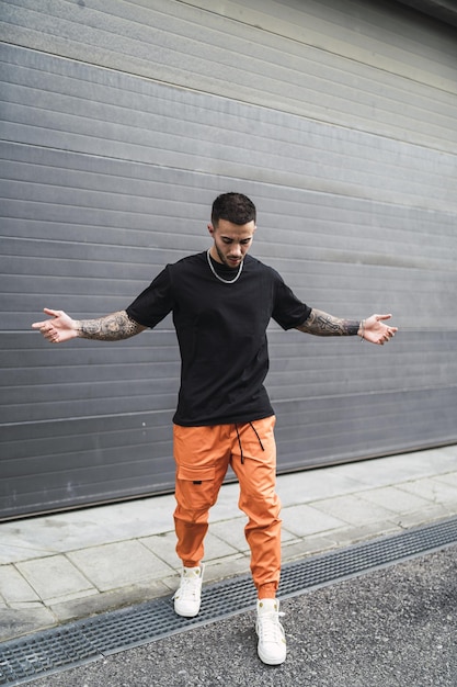 Spanish stylish man with tattoos posing in the street