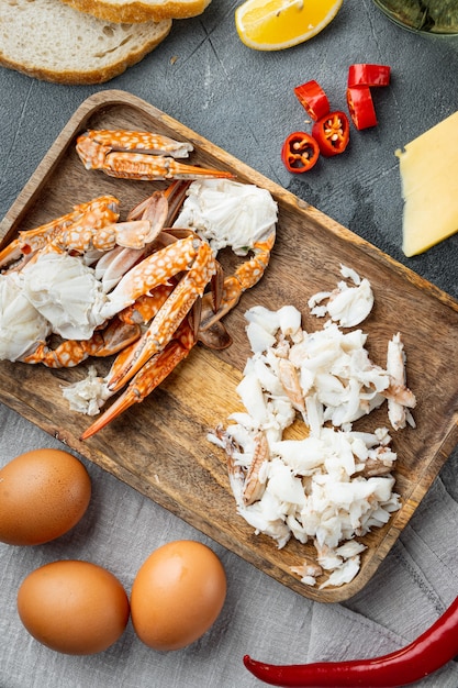 Spanish or Thai omelette ingredient, fresh red chilli, brown and white crabmeat, lemon, Cheddar cheese, eggs set, on gray background, top view flat lay