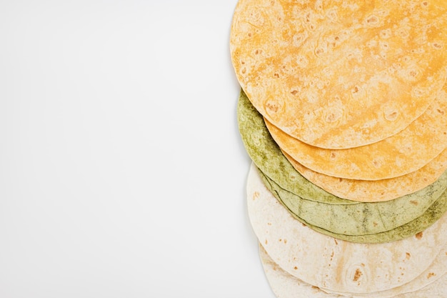 Spanish tomato spinach flavored and plain wheat tortilla wraps on white background