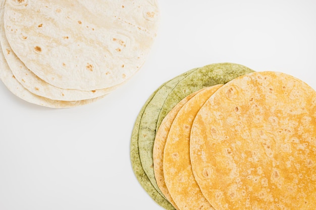 Spanish tomato spinach flavored and plain wheat tortilla wraps on white background