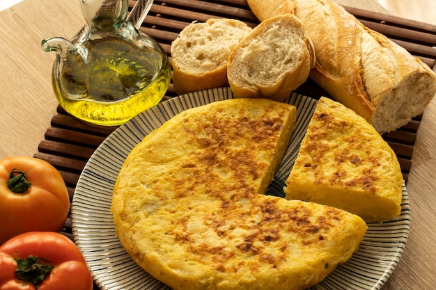 Spanish tortilla with tomatoes, garlic, bread, onions and a glass jar of olive oil