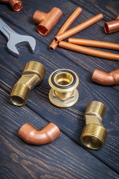 Spare parts with copper and brass accessories for plumbing repair on black vintage wooden boards