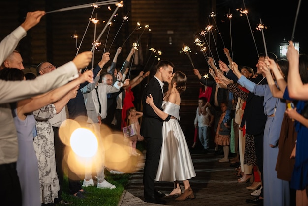 Sparklers at the wedding of the newlyweds in the hands of joyful guests