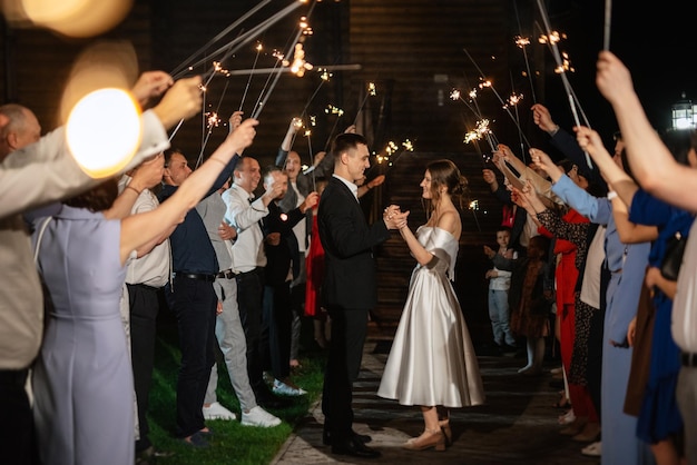 Sparklers at the wedding of the newlyweds in the hands of joyful guests