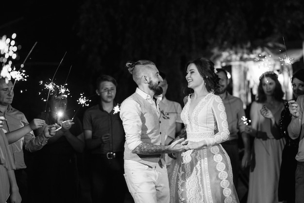 Sparklers at the wedding of the newlyweds in the hands of joyful guests