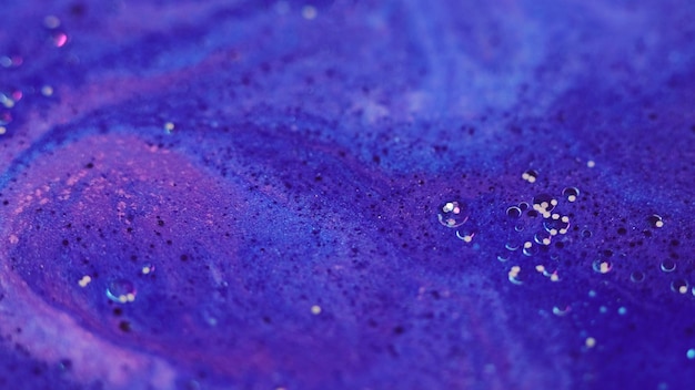 Sparkling fluid shiny ink oil drops defocused blue purple color magic gleaming soap liquid