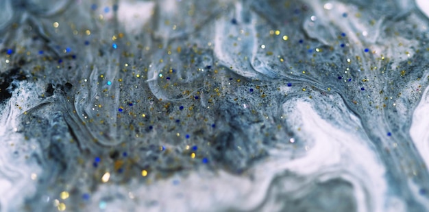 Sparkling fluid wave glitter paint flow defocused gray white color ink liquid with metallic blue