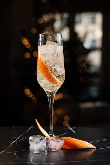 Sparkling wine in a glass with ice and orange zest