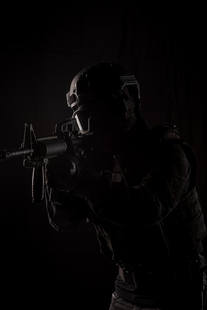 Spec ops police officer SWAT special forces with a weapon in his hands on a dark background Law and order protection concept Poster concept for police security or military