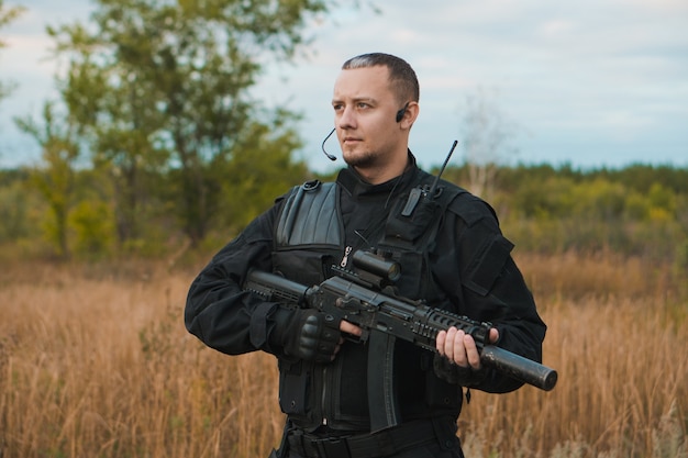 Special force soldier in black uniform with an assault rifle