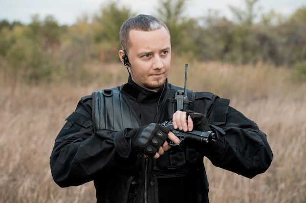 Special forces soldier in black uniform reloading a pistol