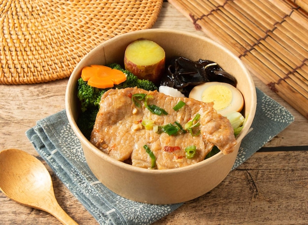 Special Pork Chop Meal Box with rice vegetables lady finger sweet potato boiled egg in bowl with wood spoon isolated on mat top view