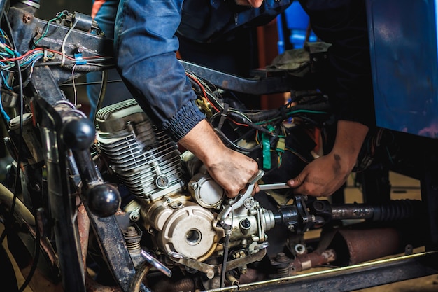 Specialist in coveralls working with motorized bicycles at repair garage. 