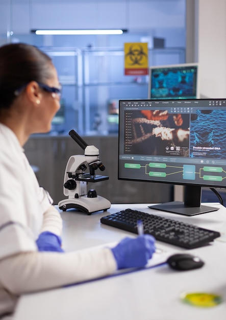 Specialist doctor analyzing virus expertise writing on clipboard during biomedical experiment in hospital laboratory, Biologist researcher working at vaccine development. Healthcare treatment