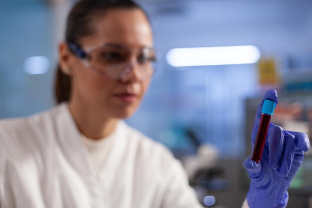 Specialist doctor holding medical test tube with blood sample analyzing dna expertise working in pharmaceutical hospital laboratory, Chemist researcher developing vaccine against coronavirus