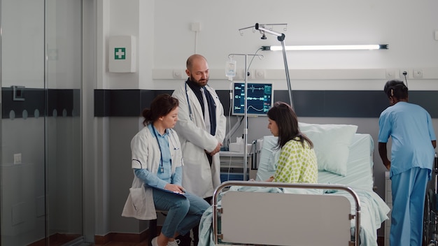 Specialist practitioner doctors monitoring sick man explaining illness treatment