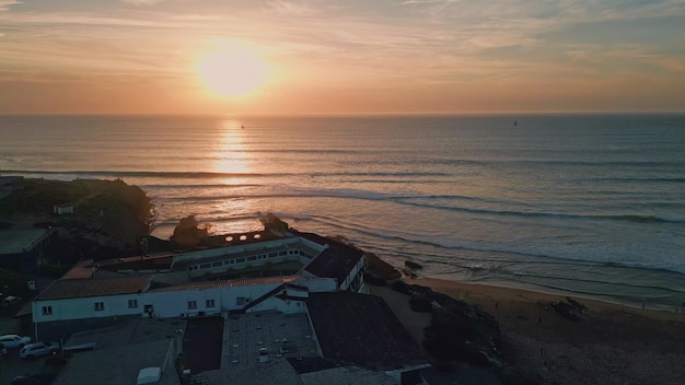 Spectacular golden sun setting down behind ocean horizon aerial waves washing