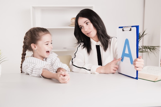 Speech therapy concept. Kid with therapist learning letters together.