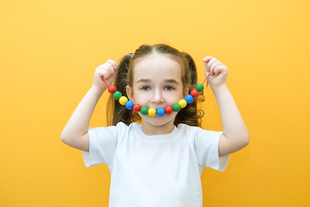 Speech therapy the development of fine motor skills Toddler girl stringing beads on a string happy child