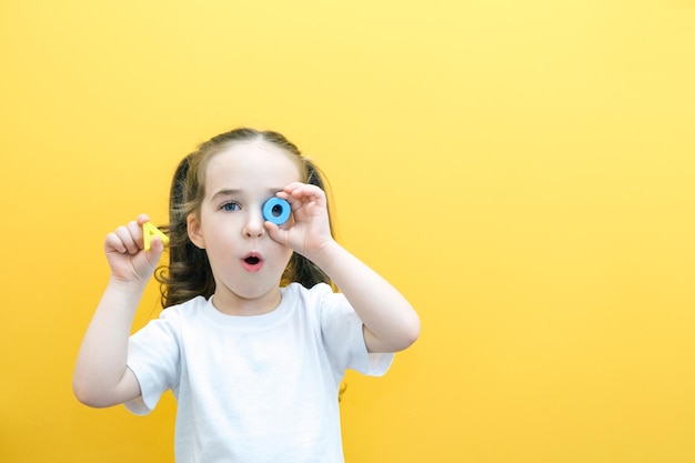 Speech therapy Toddler girl holding the letter O and A in her hands Classes with a speech therapist Girl on isolated yellow background