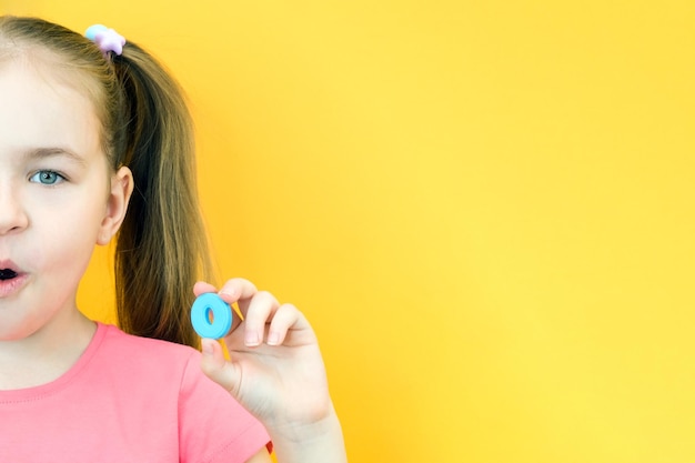 Speech therapy Toddler girl holding the letter O in her hands Classes with a speech therapist Girl on isolated yellow