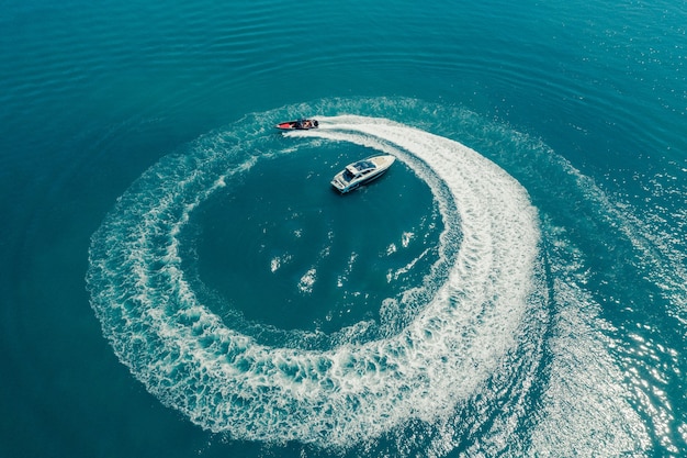 Speed boat in andaman sea making a circle from bubbles, aerial view