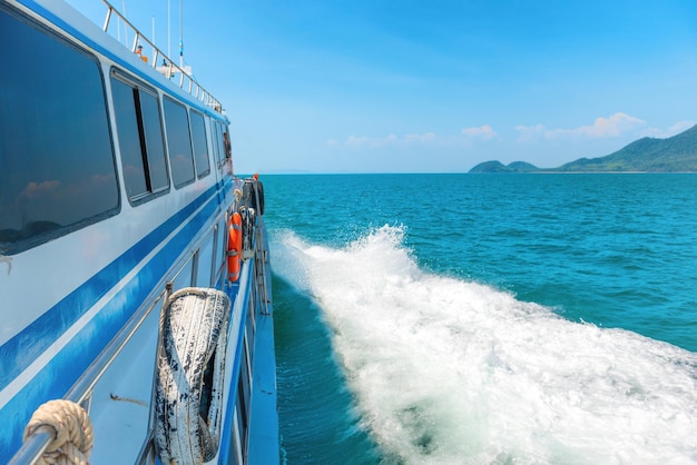 Speed boat with white wake stream in blue sea water. Side view