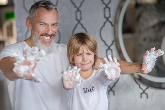 Spending time together. A man and a boy playing with shaving foam