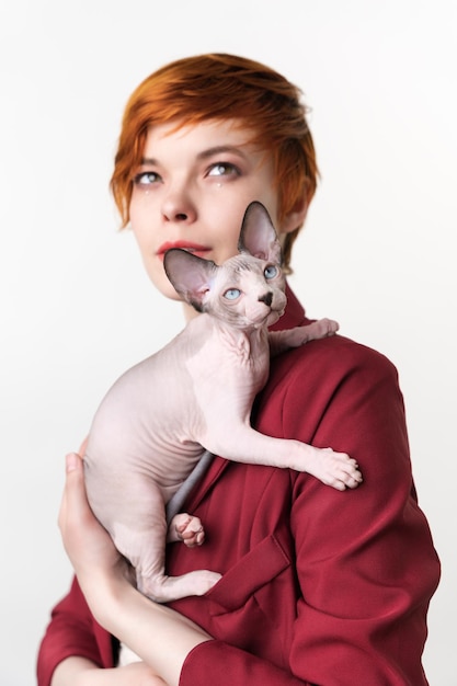 Sphynx Cat sitting on shoulder of hipster redhead young woman Selective focus on foreground kitten