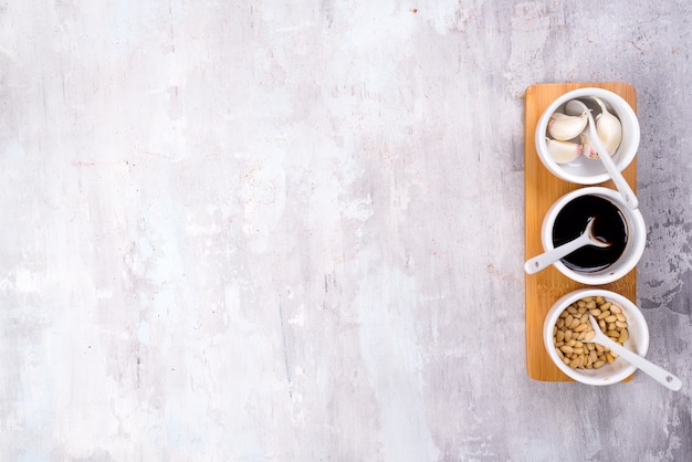 Photo spice pine nuts, soy sauce and garlic on a bowl gray stone background with copy space