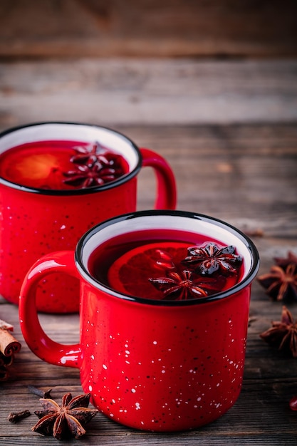 Spiced Pomegranate Apple Cider Mulled Wine Sangria in red mugs on wooden background Hot drinks for Christmas