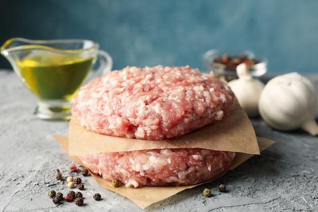 Spices and baking paper with minced meat on grey, close up