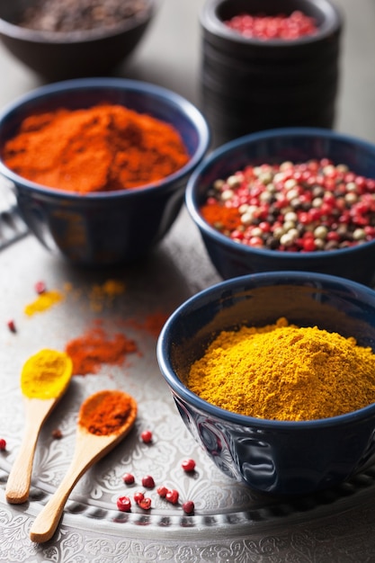 Spices in bowls: curry, pink and black pepper, paprika powder