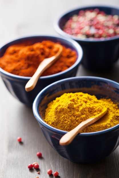 Spices in bowls: curry, pink and black pepper, paprika powder