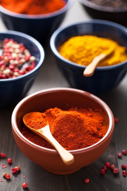 Spices in bowls: curry, pink and black pepper, paprika powder