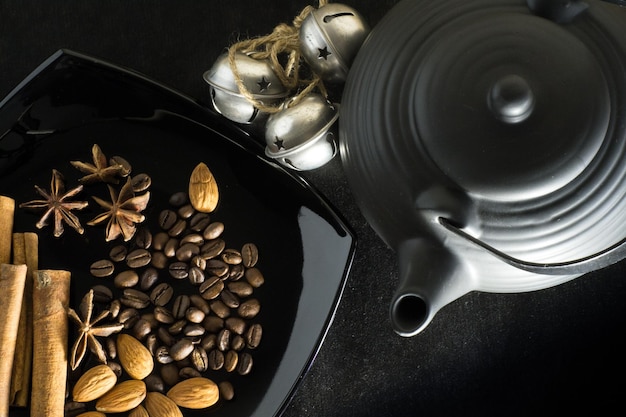 Spices of coffee beans with a teapot and bells on a black background