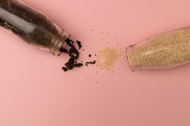 Spices in glass jars on a pink background