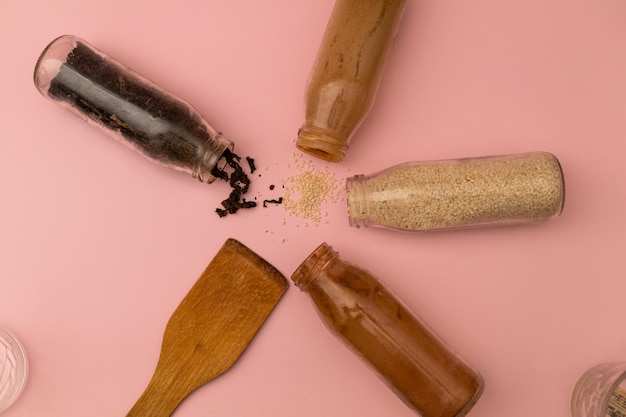 Spices in glass jars on a pink background