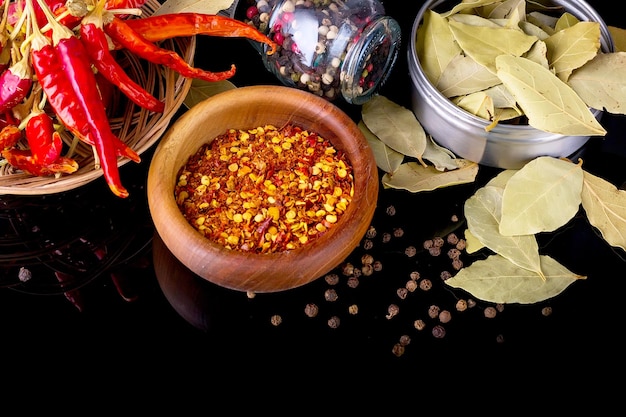 Photo spices and herbs bay leaf black pepper and wooden bowl of chili flakes