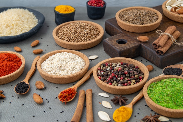 Spices lie in bowls and wooden spoons, top view, soft focus. Spices and seasonings for cooking in the composition on the table.