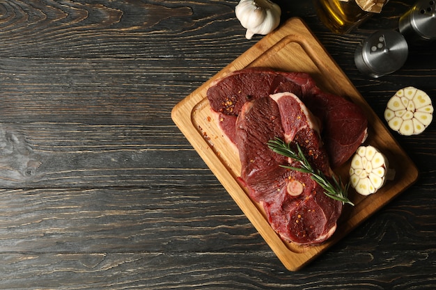 Spices, oil and board with raw steak meat on wooden