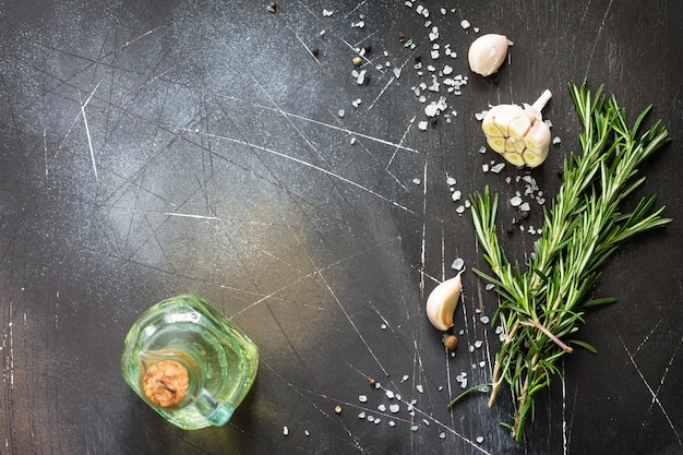 Spices olive oil  and herbs on a dark stone or slate table Ingredients for cooking