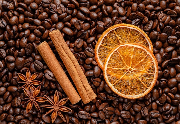 Spices on roasted coffee beans background. Directly above, flat lay.